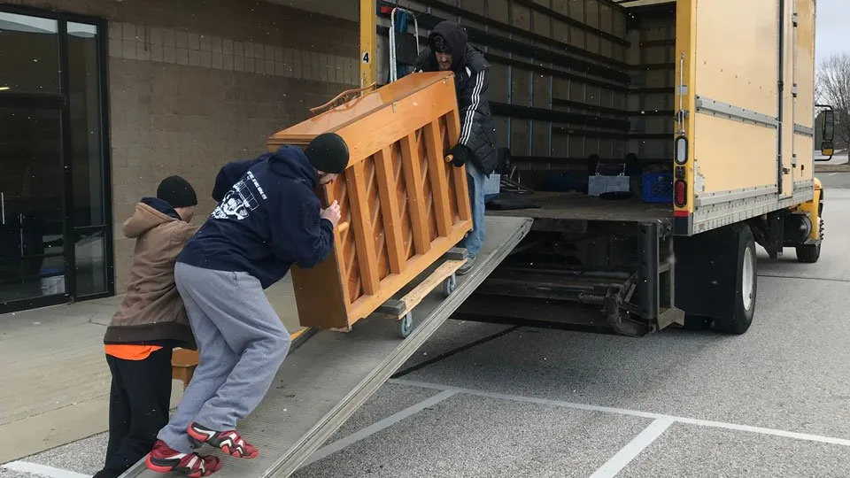 A man pushes a properly packaged piano up a ramp.
