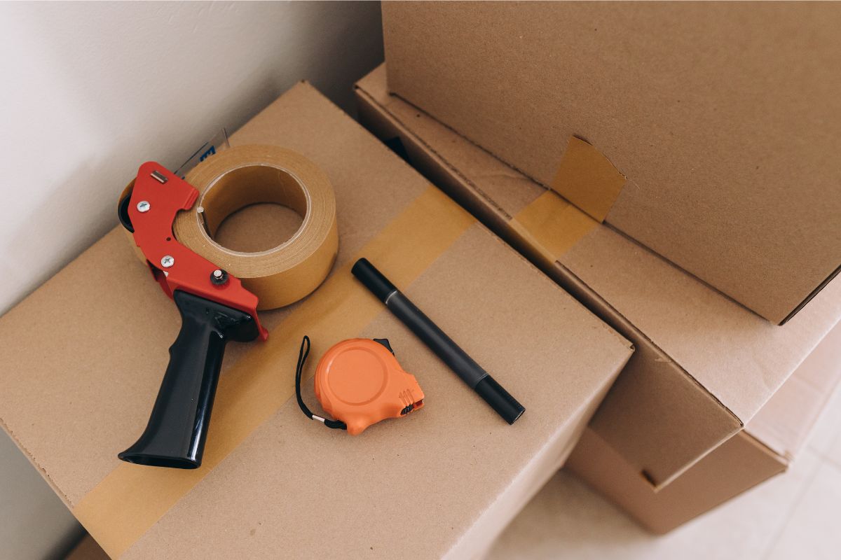 moving boxes with packing tape dispenser, marker, and tape measure on top