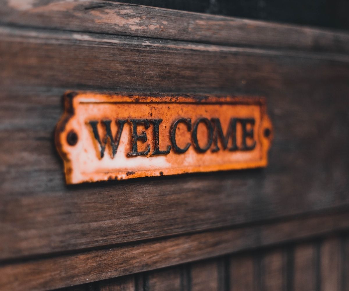 Dark wooden door with rustic metal welcome sign