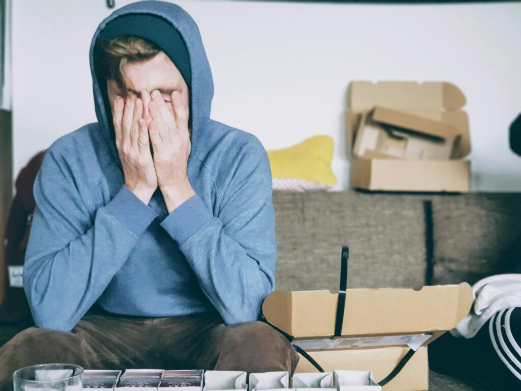 Weary mover urgently packing in a rustic Asheville apartment filled with messy boxes, scattered belongings, and everyday items.