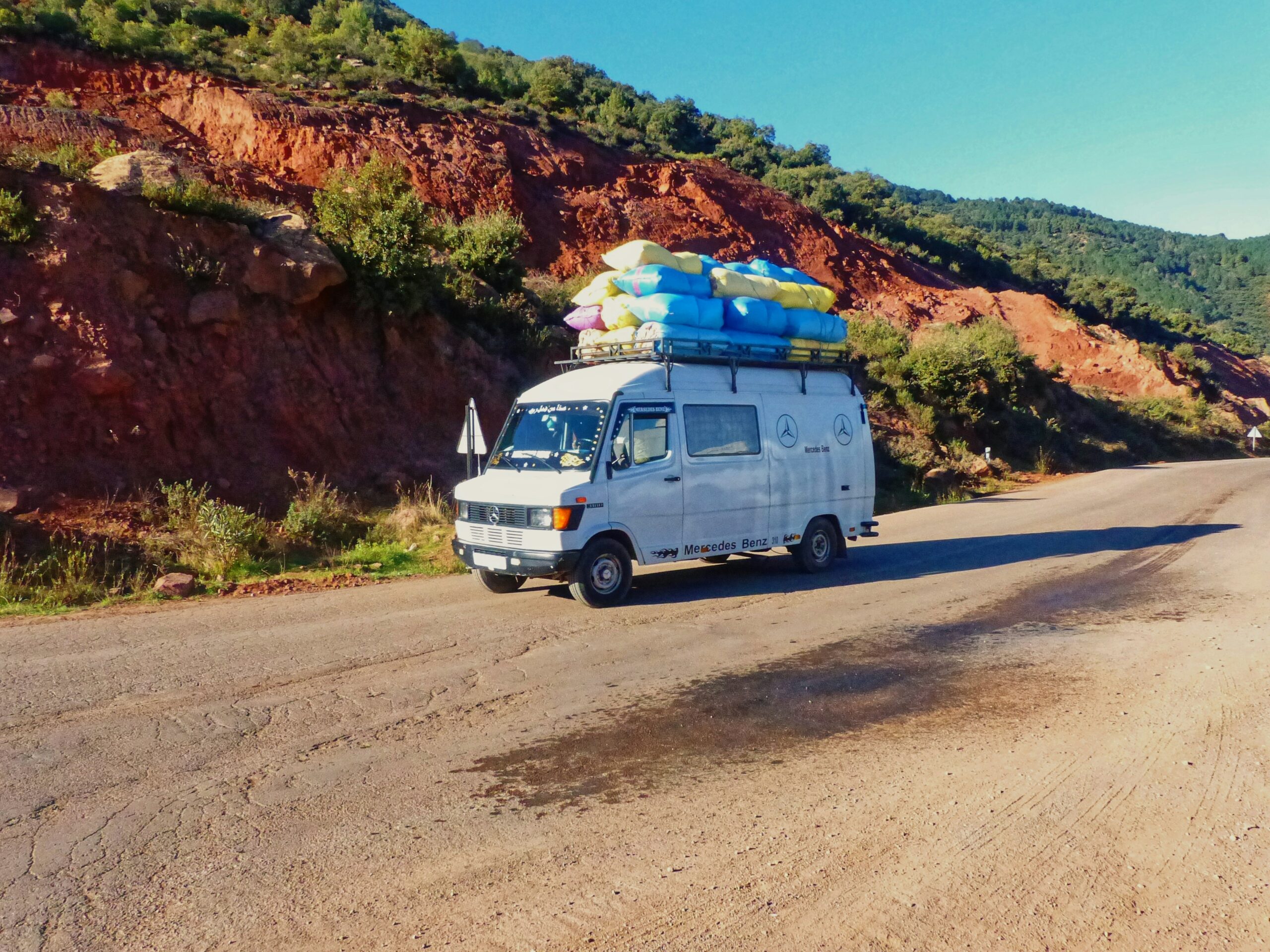 Morning light and mountain views frame the tense, chaotic scene as a rented moving truck waits outside amid lush greenery and blooming rhododendrons.