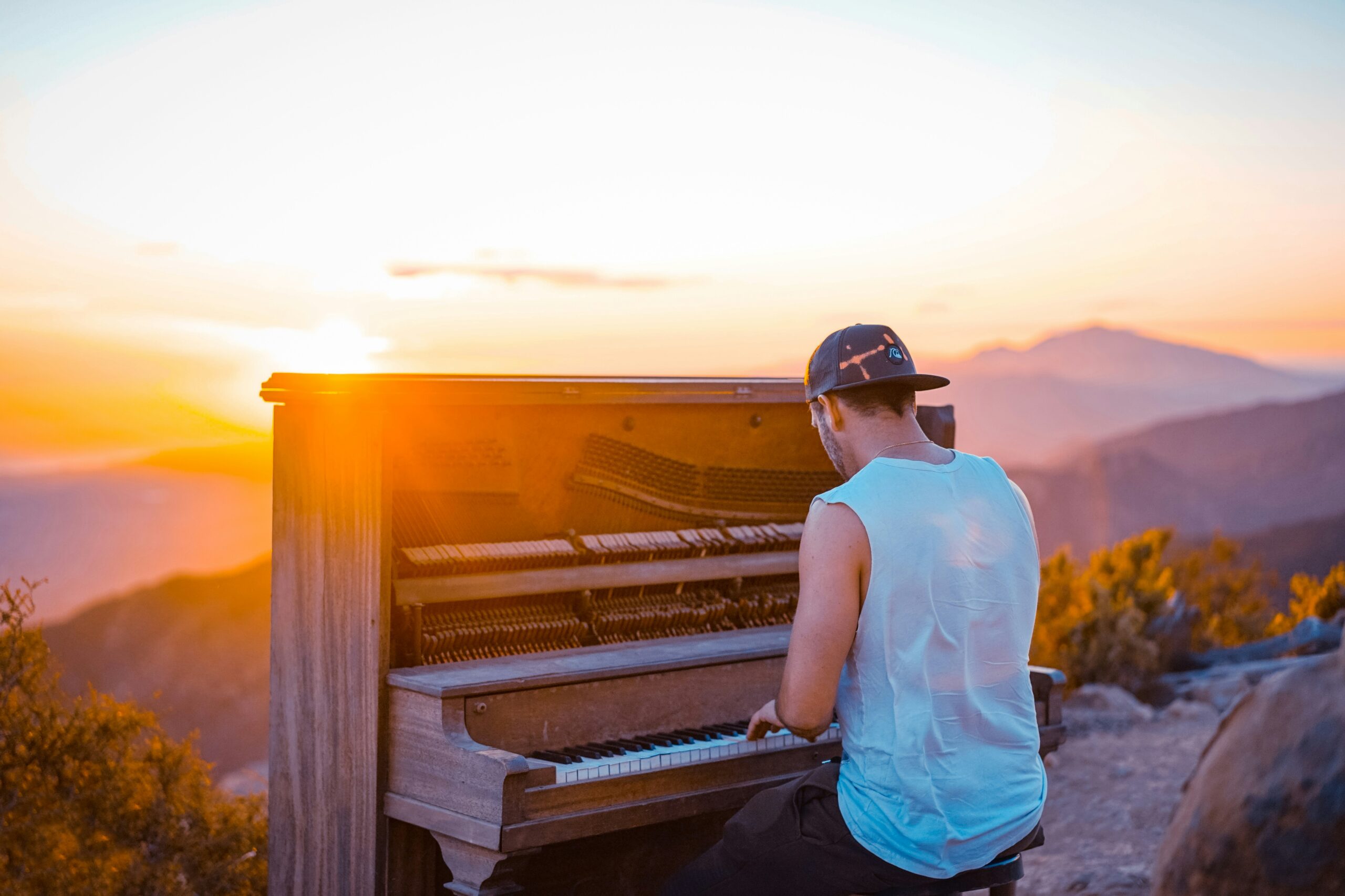 Man playing piano outdoors while the sun sets.