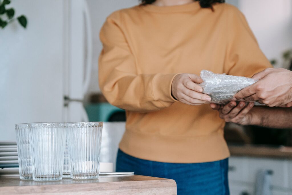 A home owner carefully wraps fragile dishes in bubble wrap before moving.