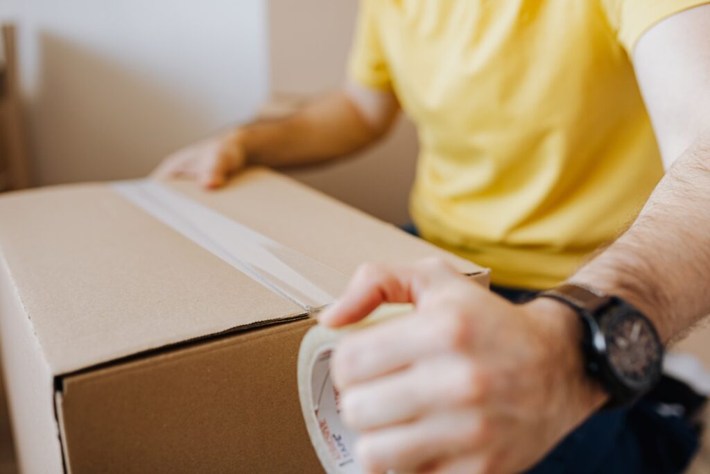 Man confidently tapes up a box for moving after carefully packing its contents.